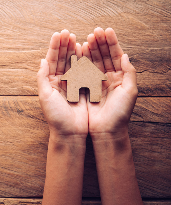 Hands holding wood cutout of a house